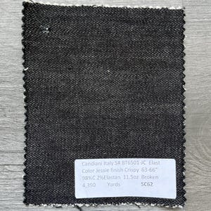 May include: A dark gray denim fabric swatch with a white selvage edge. The fabric has a textured appearance. A white label displays the text "Candiani Italy S# BT6501-JC Elast Color Jessie finish Crispy 63-66" 98%C 2%Elastan 11.5oz Broken 4,390 Yards SC62."