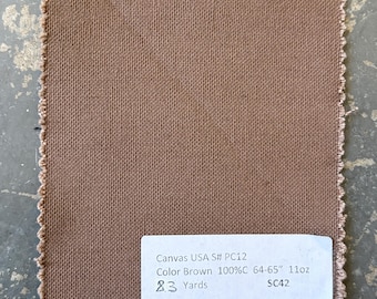 Può includere: Un campione quadrato di tessuto di tela marrone con bordi sfilacciati. Un'etichetta bianca mostra il testo: "Canvas USA S# PC12 Color Brown 100%C 64-65" 11oz 23 Yards SC42". Il tessuto sembra essere un campione di un materiale più pesante.