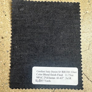 May include: A black denim fabric swatch with a white label that reads "Candiani Italy Denim S# RR5501 Elast Color Blend finish Fluid 11.75oz 98%C 2% Elastan 61-63" 3x1R 12,800 Yards".