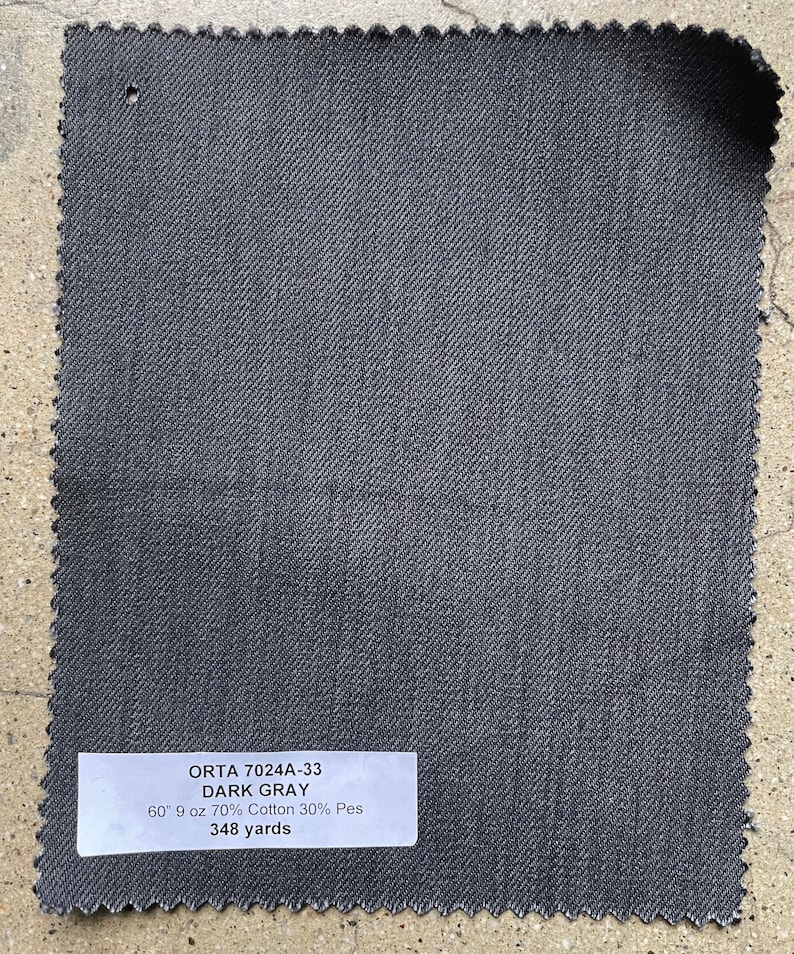 May include: A dark gray fabric swatch with the text "ORTA 7024A-33 DARK GRAY 60 9 oz 70% Cotton 30% Pes 348 yards" printed on a white label.