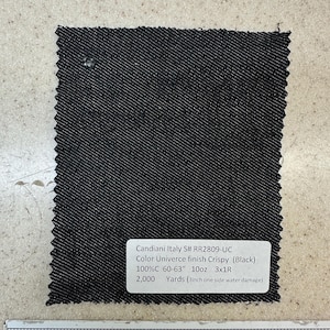 May include: A black fabric swatch with a white label that reads "Candiani Italy S# RR2809-UC Color Univerce finish Crispy (Black) 100%C 60-63" 10oz 3x1R 2,000 Yards (3inch one side water damage)". The fabric swatch is measured with a ruler in inches.