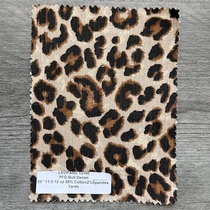 Könnte beinhalten: Stoffmuster mit Leopardenmuster mit braunen und schwarzen Flecken auf beigem Hintergrund. Das Etikett lautet: "LEOPARD 13396 PFD Bull Denim 142cm 11.5-12 oz 98% Cotton2% Spandex Yards."