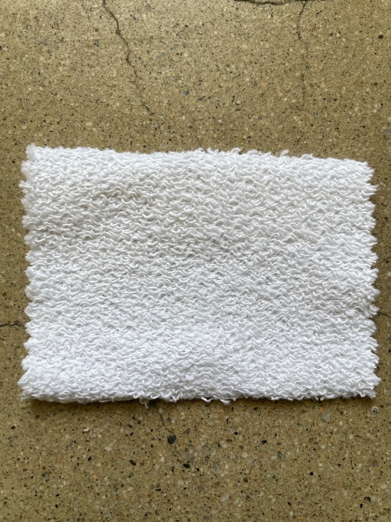 May include: White terry cloth fabric with a textured surface.