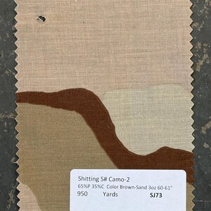 May include: A fabric swatch with a camouflage pattern in shades of brown and tan. The fabric has a textured appearance and a jagged edge. A white label displays the text "Shitting S# Camo-2" and other details.