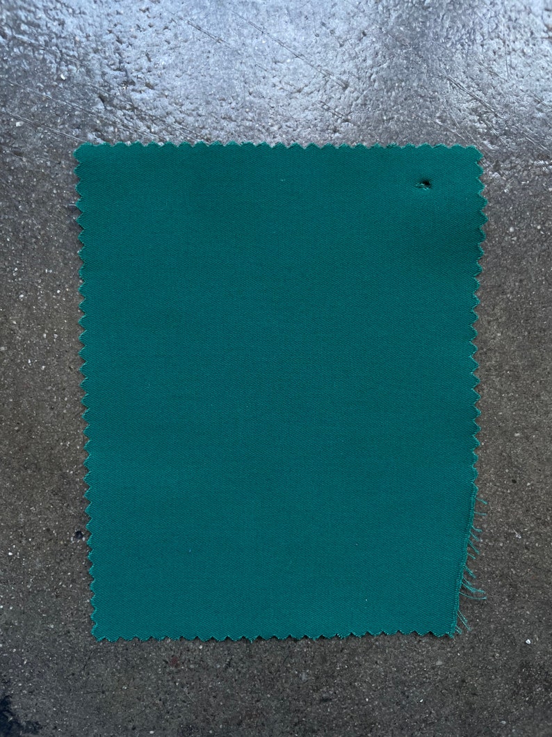 May include: A solid teal green fabric swatch with a slightly rough texture.