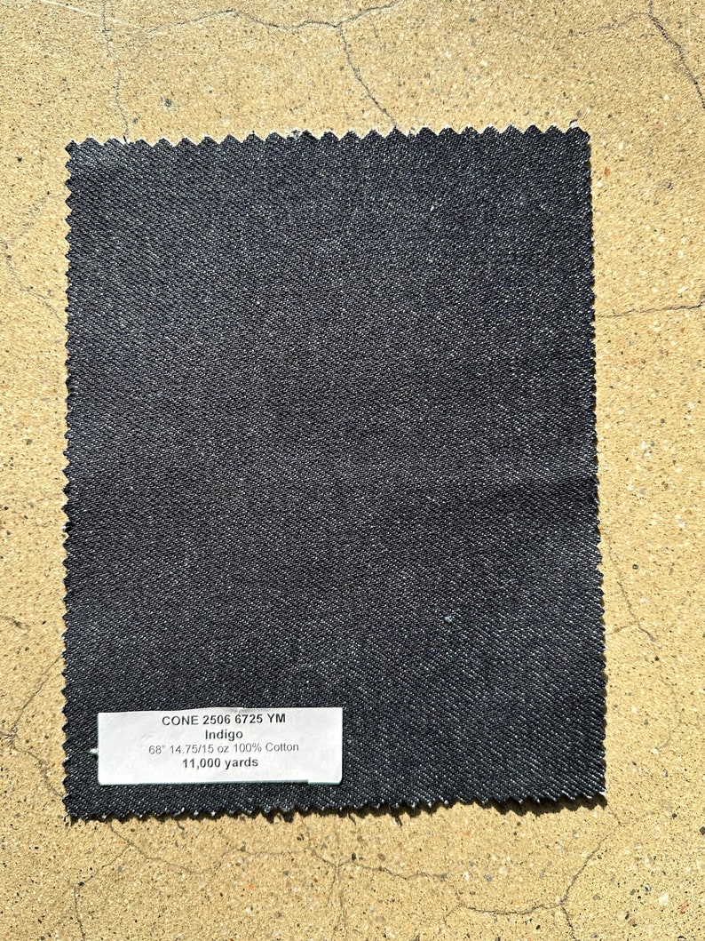 May include: A dark indigo denim fabric swatch with the text "CONE 2506 6725 YM Indigo 68 14.75/15 oz 100% Cotton 11,000 yards" printed on a white label.