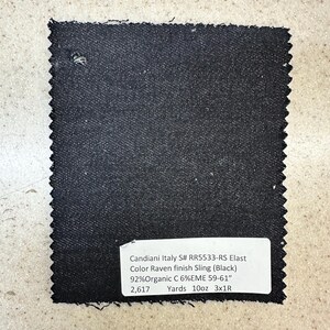 May include: A black fabric swatch with a white label that reads "Candiani Italy S# RR5533-RS Elast Color Raven finish Sling (Black) 92% Organic C 6%EME 59-61" 2,617 Yards 10oz 3x1R"
