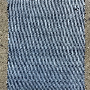 May include: A close-up of a piece of blue denim fabric with a woven texture.