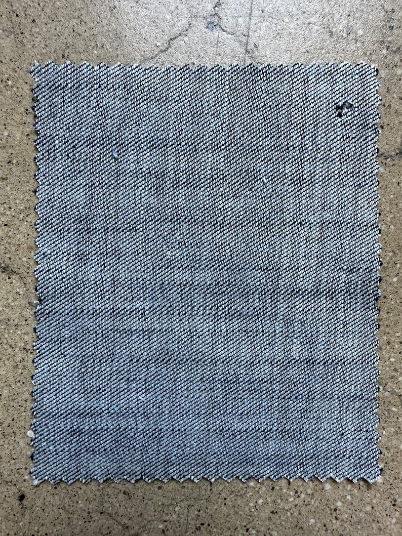 May include: A close-up of a piece of blue denim fabric with a woven texture.