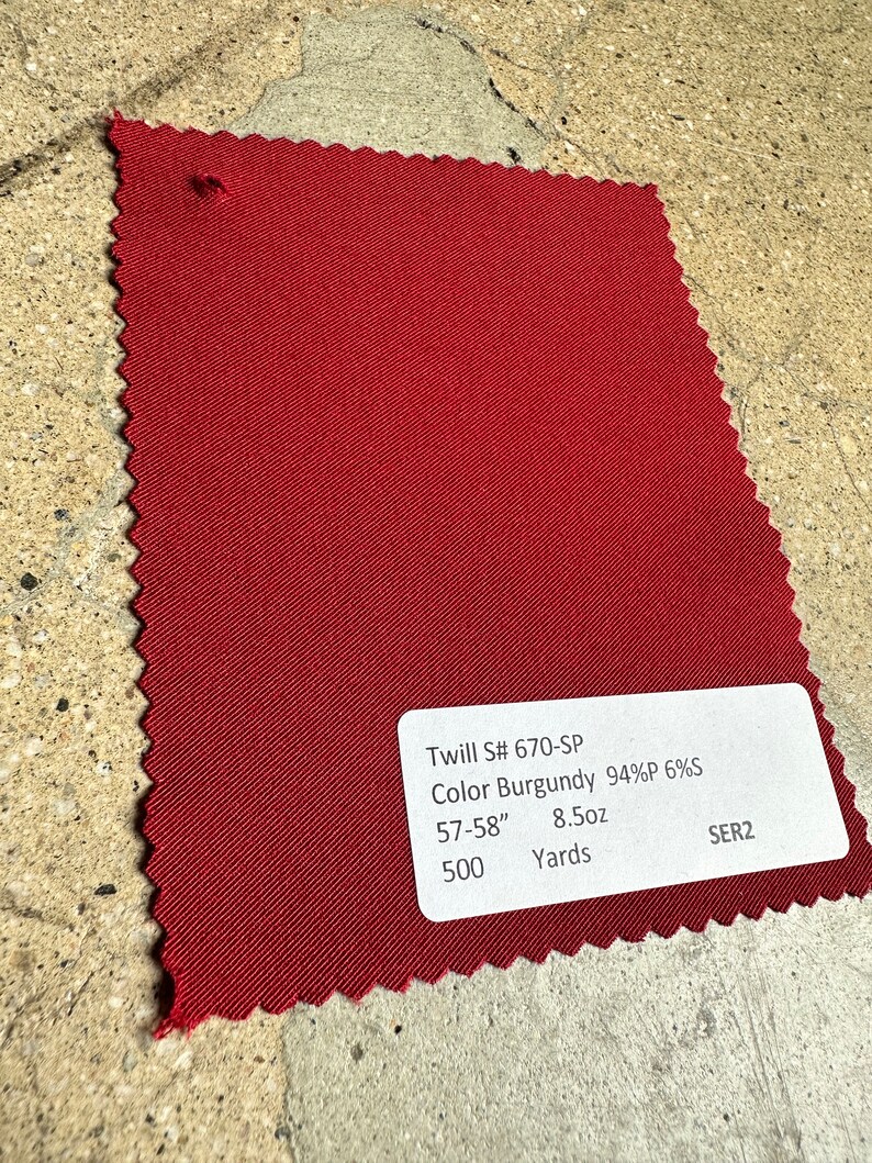 May include: A burgundy twill fabric swatch with the text "Twill S# 670-SP Color Burgundy 94%P 6%S 57-58" 8.5oz 500 Yards SER2".