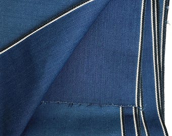 Può includere: Primo piano di un pezzo di stoffa blu piegato con strisce bianche e nere lungo il bordo.