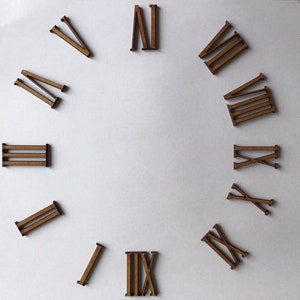 May include: A set of twelve wooden Roman numeral clock numbers. The numbers are in a circle on a white background.