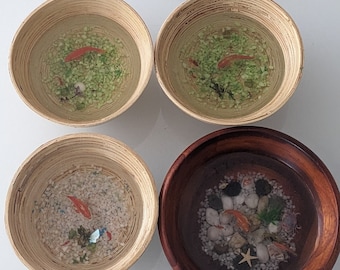 May include: Four resin bowls with different scenes inside. Two bowls are made of light brown bamboo and feature a green and white background with orange goldfish. One bowl is made of light brown bamboo and features a white background with orange goldfish and blue and green accents. The last bowl is made of dark brown wood and features a white background with orange goldfish, white rocks, and a starfish.
