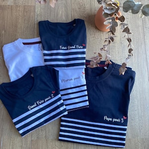 Peut inclure: Quatre t-shirts rayés bleu marine et blanc avec des textes différents sur chacun. Le texte sur les t-shirts est "Futur Grand Frere", "Maman pour 3", "Grand Frere pour 2", et "Papa pour 3".