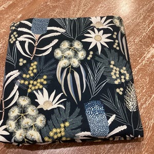 May include: Black fabric with a white and blue floral pattern featuring Australian native flowers like banksia and wattle.