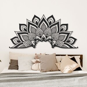 Puede incluir: Decoraci&oacute;n de pared de mandala en blanco y negro con detalles intrincados, colgada sobre una cama con almohadas y una colcha blanca.