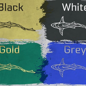 May include: An image showcasing four color options for a shark-shaped wall art. The options are black, white, gold, and grey, each displayed on a textured background with the color name above the shark design.