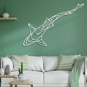 May include: White metal shark wall art. The artwork is mounted on a green wall above a white sofa with striped pillows. A guitar and decorative shelves are also visible in the room.