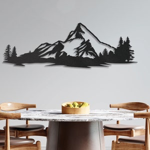 May include: Black metal wall art depicting a mountain range with snow-capped peaks and pine trees. The art is displayed above a wooden table with chairs.