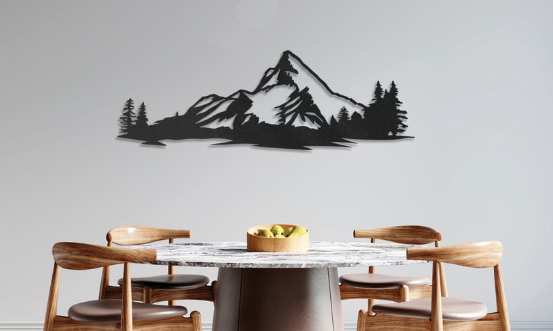 May include: Black metal wall art depicting a mountain range with snow-capped peaks and pine trees. The art is displayed above a wooden table with chairs.
