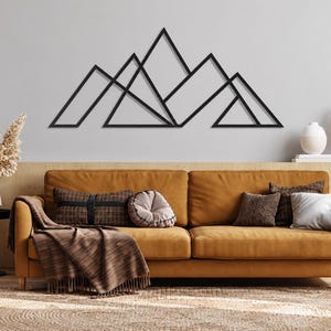May include: A black metal wall art piece featuring a geometric mountain range design with sharp, angular peaks and interconnected lines. The structure consists of multiple triangles of varying sizes arranged in a horizontal, linear formation.