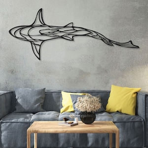 May include: A black metal shark wall art decorates a gray wall above a blue sofa with yellow pillows. A cactus in a pot and a woven pendant light are also visible in the room. The shark is a modern, abstract design.