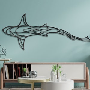 May include: A black metal shark wall art piece. The artwork is mounted on a light blue wall above a modern style cabinet. The shark is depicted in a stylized, geometric design, with a sleek, minimalist aesthetic. The room is decorated with modern furniture.