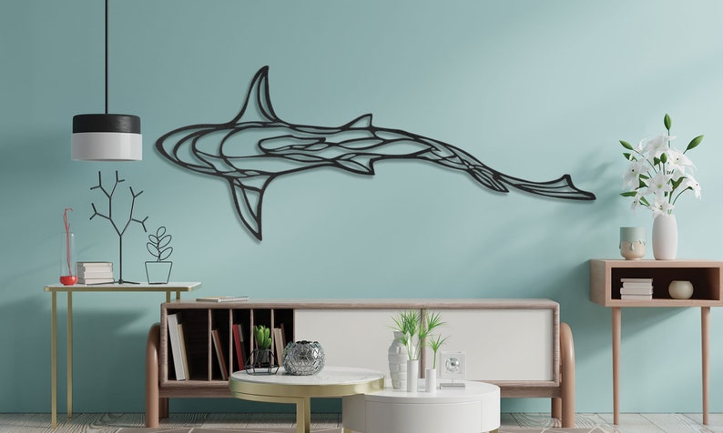 May include: A black metal shark wall art piece. The artwork is mounted on a light blue wall above a modern style cabinet. The shark is depicted in a stylized, geometric design, with a sleek, minimalist aesthetic. The room is decorated with modern furniture.