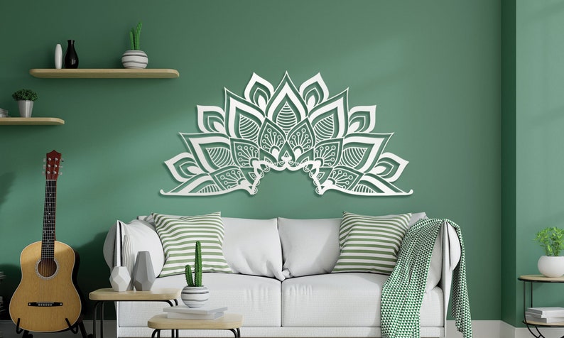 Puede incluir: Arte de pared decorativo blanco en forma de mandala semicircular con intrincados patrones florales. El arte est&aacute; montado en una pared verde sobre un sof&aacute; blanco con almohadas a rayas.