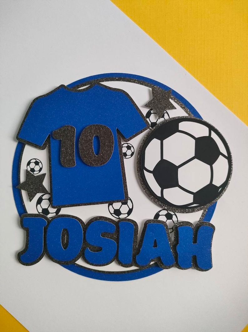 May include: Blue and black soccer-themed cake topper with the name Josiah and the number 10.