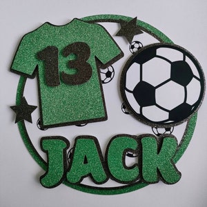 May include: Green and black glitter cake topper with a soccer ball, a green jersey with the number 13, and the name Jack.