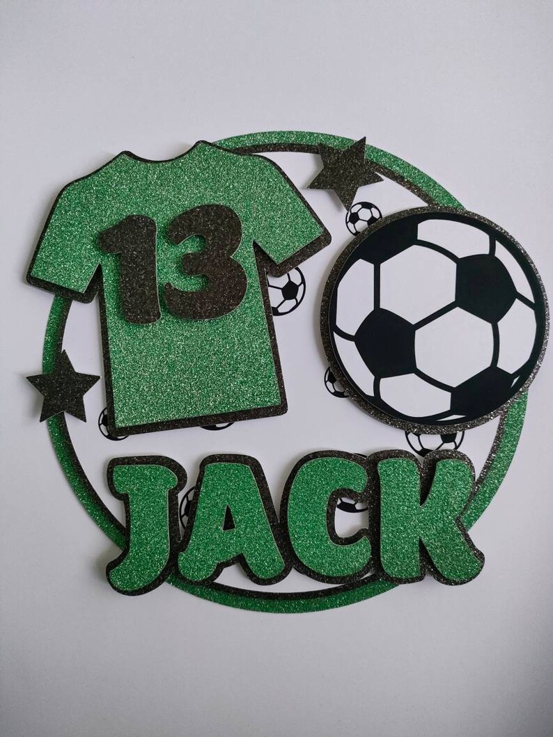 May include: Green and black glitter cake topper with a soccer ball, a green jersey with the number 13, and the name Jack.