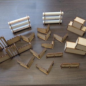 May include: A collection of miniature building components, including white PVC pipes held together with brown supports, and various laser-cut wooden pieces. The wooden pieces include corner sections, walls, and container-like structures, all in a natural wood color.