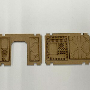 Puede incluir: Componentes de madera cortados con l&aacute;ser para un modelo en miniatura. Las piezas son de color marr&oacute;n claro y sin terminar. El conjunto incluye un marco de puerta, una secci&oacute;n de pared con una puerta y una secci&oacute;n de pared m&aacute;s grande.