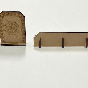 Puede incluir: Dos piezas de madera cortadas con l&aacute;ser. Una es una puerta con un dise&ntilde;o circular en el centro y detalles de pernos hexagonales. La otra es una pieza rectangular con tres patas de soporte. Ambas piezas son de color marr&oacute;n claro.