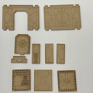 Puede incluir: Un conjunto de piezas de madera sin terminar, cortadas con l&aacute;ser, para una estructura en miniatura de ciencia ficci&oacute;n o industrial. El conjunto incluye paredes, puertas y paneles con dise&ntilde;os geom&eacute;tricos y mec&aacute;nicos, listos para montar y pintar.