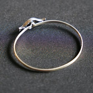 May include: A silver bangle bracelet with a unique clasp design.