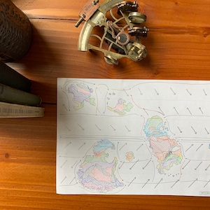 Puede incluir: Un mapa del mundo dibujado a mano con continentes coloridos y flechas que indican los patrones de viento. El mapa está en una hoja de papel blanco y está rodeado de una superficie de madera.