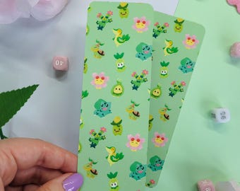 May include: Two rectangular bookmarks with a light green background featuring a repeating pattern of small, colorful cartoon creatures including green turtles, pink flowers, and yellow-headed figures with green leaves, arranged in a grid-like layout.