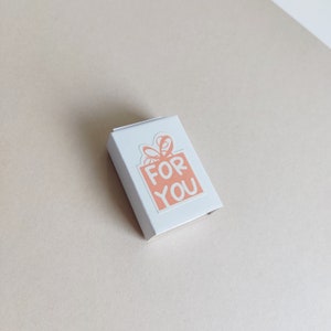 May include: A white box with a pink gift box sticker that says "FOR YOU" on it.