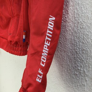 May include: Red mesh jacket with white embroidered text "ELF COMPETITION" on the sleeve.