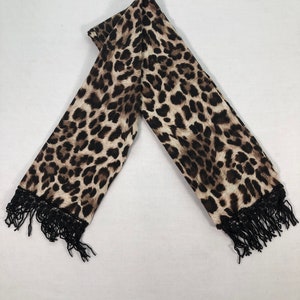 May include: A brown and black leopard print scarf with black fringe on the ends.