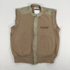 May include: A tan sleeveless vest with a full-length zipper and two front pockets. The vest features suede shoulder patches and a suede strip down the center. The word "SKYLINE" is printed on the chest.