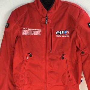 May include: Red motorcycle jacket with a black zipper and black accents. The jacket has the text "ELF MOTO RANGE" and "elf moto sports" printed on it.