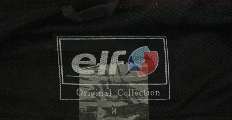 May include: A black and white label with the text "elf Original Collection" and a logo with a blue and red design. The label is attached to a black fabric.
