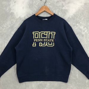 Pode incluir: Uma camisa de moletom azul marinho com um logotipo bordado em amarelo e preto que diz "Penn State" e "Nittany Lions".