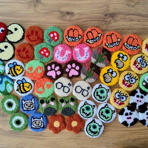 Puede incluir: Una colección de 35 posavasos redondos de crochet de colores vivos con varios personajes de dibujos animados y diseños, incluyendo Pac-Man, abejas, flores y personajes de dibujos animados como Bob Esponja y el Grinch.