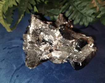 May include: A cluster of black and clear quartz crystals with a silvery sheen. The crystals are arranged in a random pattern and have a rough, natural texture.