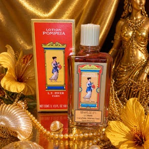 Pode incluir: Uma garrafa vintage de perfume Lotion Pompeia e sua caixa combinando. A garrafa e a caixa apresentam uma mulher em um vestido cl&aacute;ssico. O fundo inclui tecido dourado, uma est&aacute;tua dourada e flores amarelas. A garrafa cont&eacute;m 100 ml.