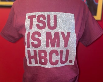 Op de afbeelding: Bordeauxkleurig T-shirt met een zilveren glittervierkant waarop "TSU is my HBCU." staat.